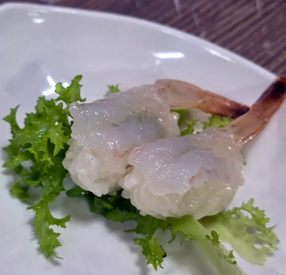 A glossy plate of raw shrimp sushi