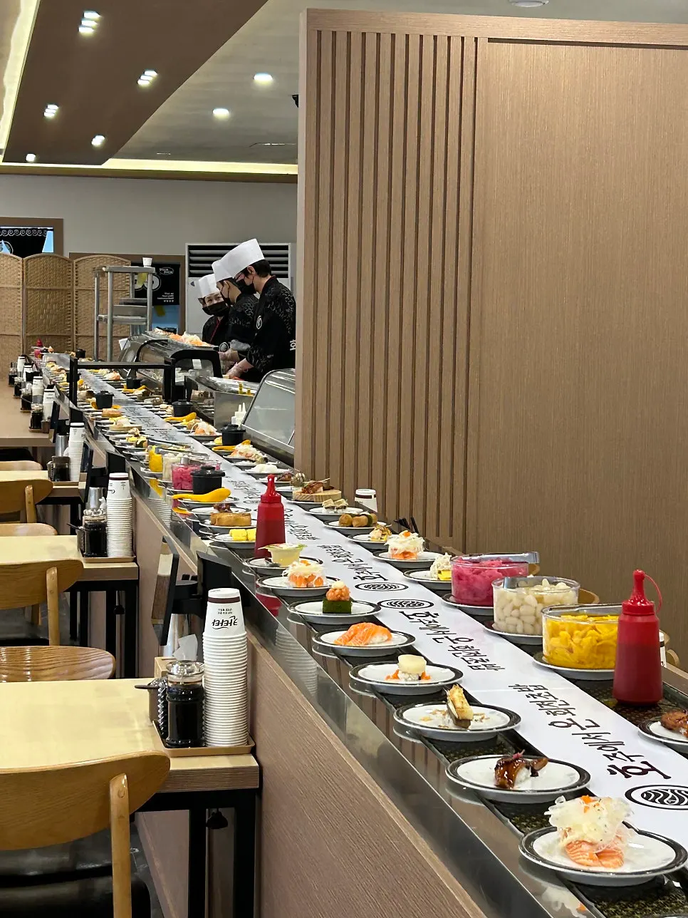 우드톤 조명의 회전초밥 매장 내부