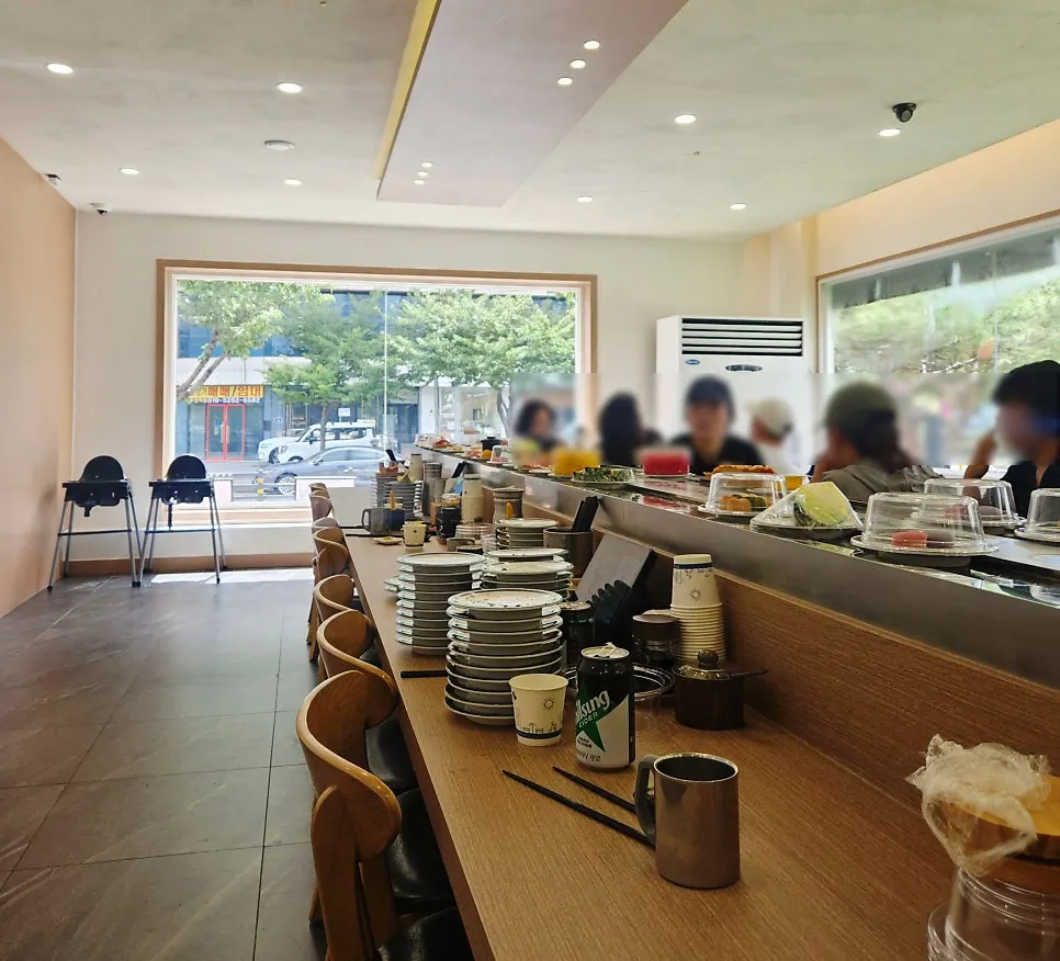 Interior of the conveyor sushi restaurant crowded with lunchtime customers