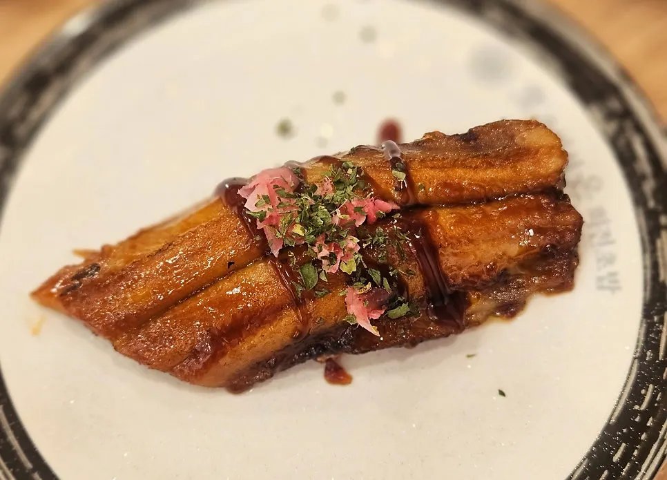 A plate of eel sushi topped with sauce