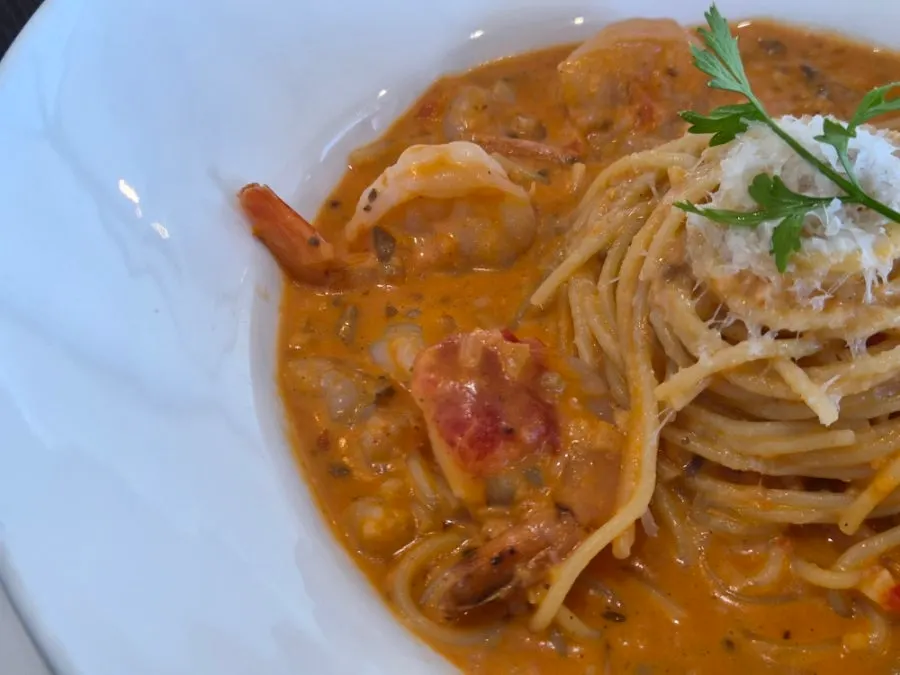 A large whole shrimp on top of the rosé pasta