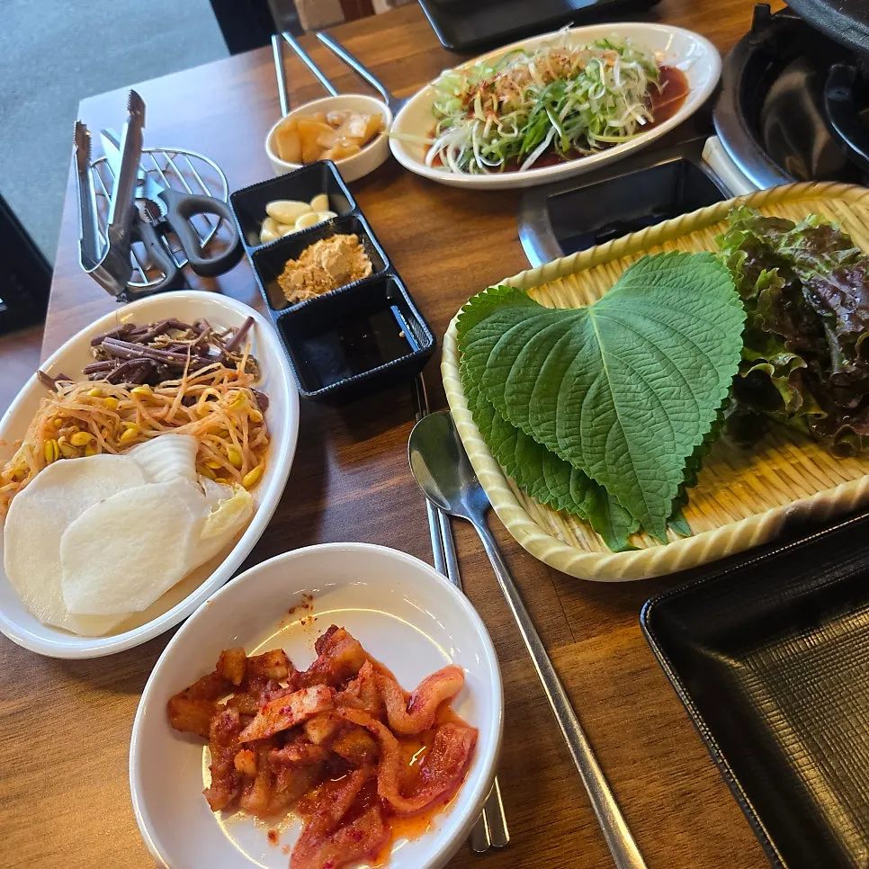 Side dishes at Neolpanji including green onion salad and wrapping vegetables