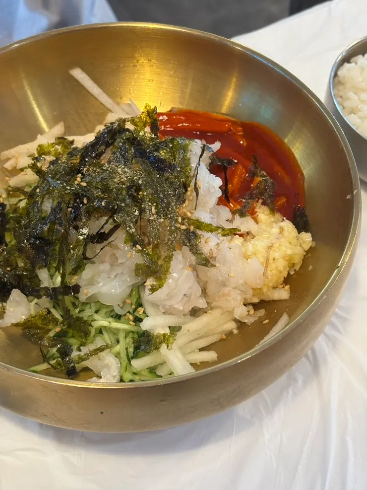 A bite of abalone squid mulhoe topped with kimchi