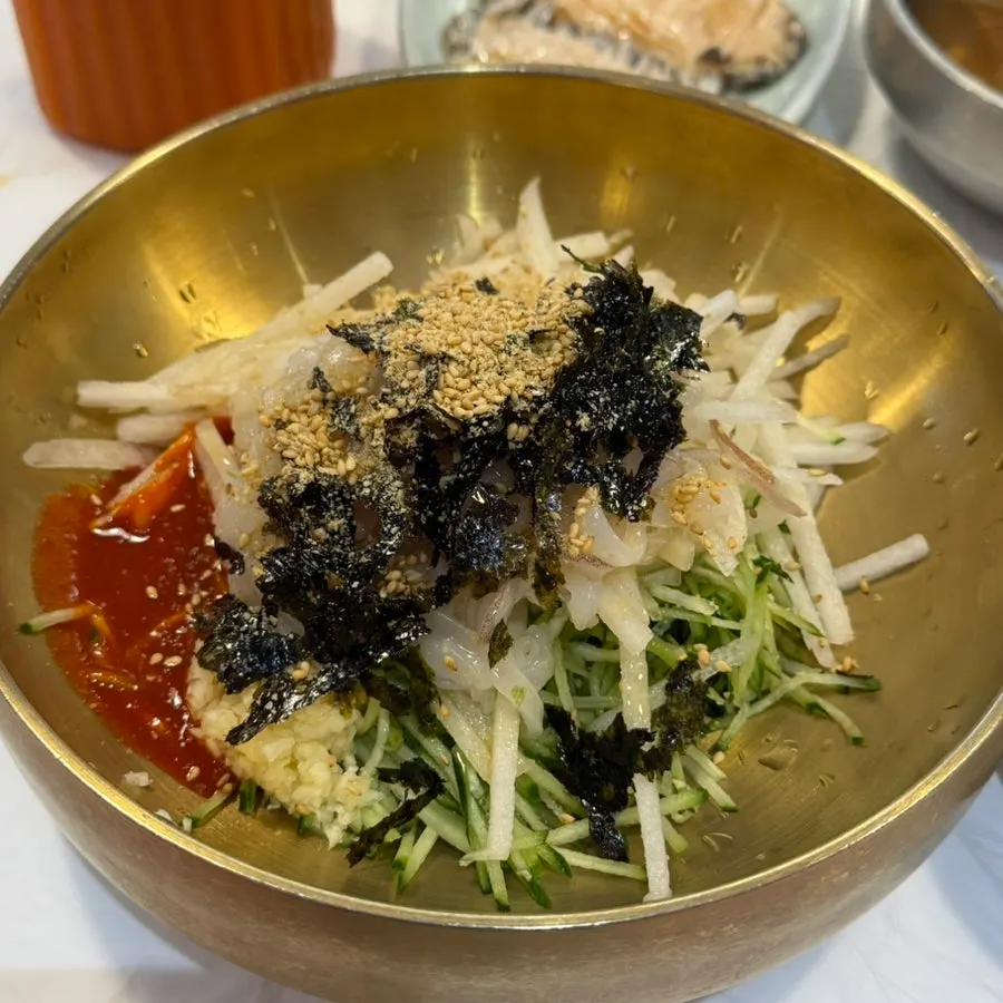 Two freshly served bowls of mulhoe with abalone side dish