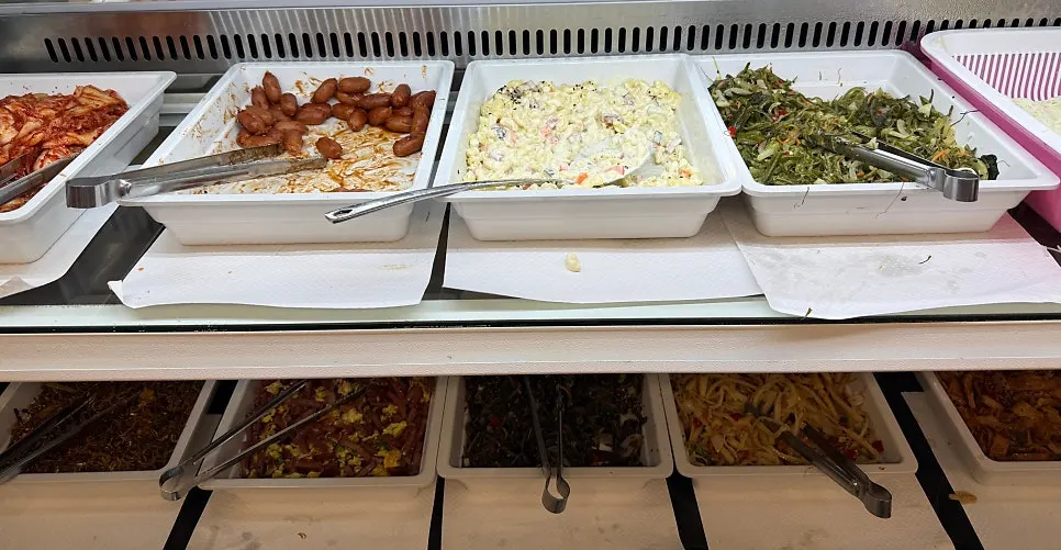 Self-serve side dishes including stir-fried sausage and corn salad