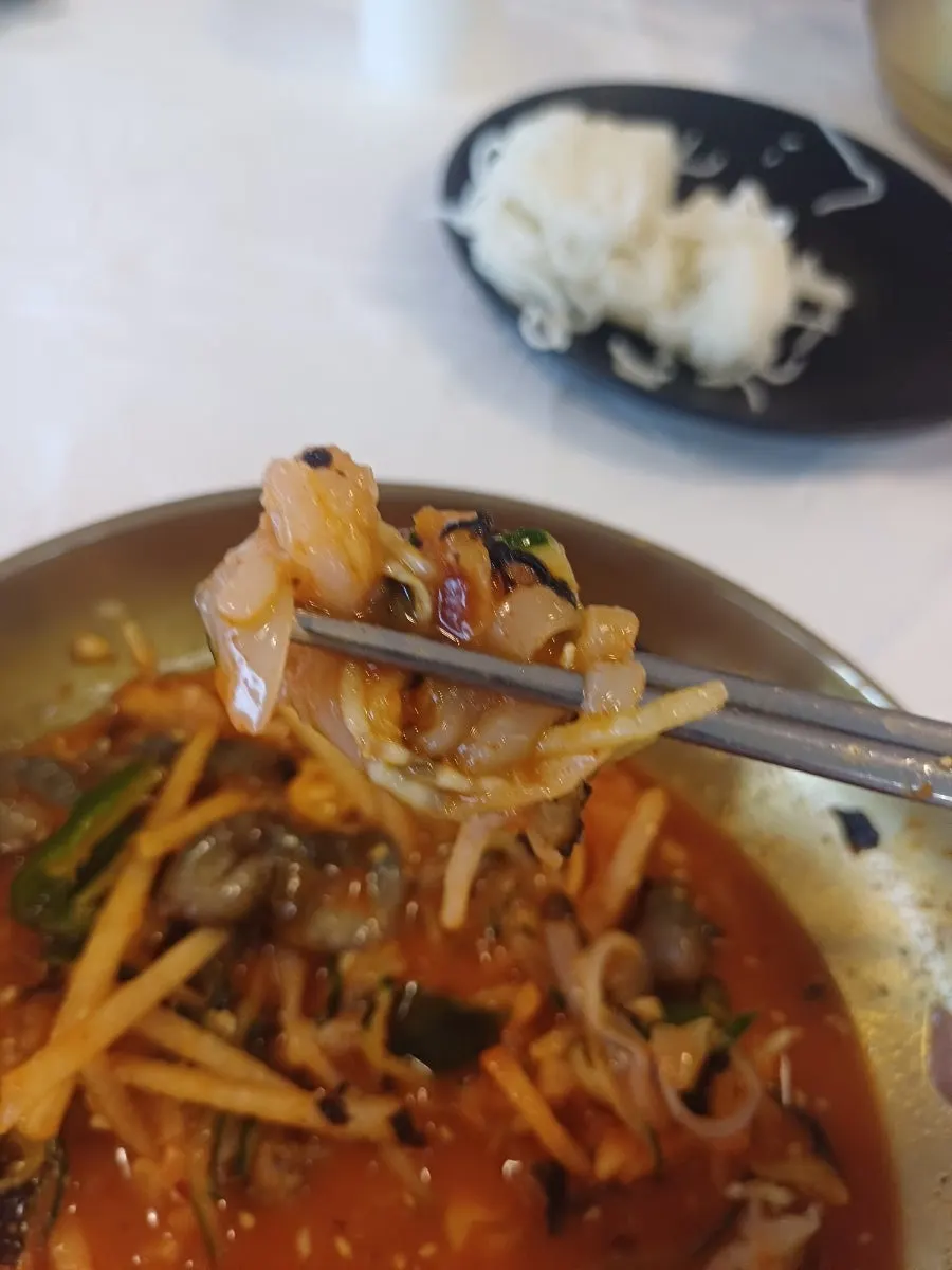 A spoonful of mulhoe with gim flakes and vegetables mixed in