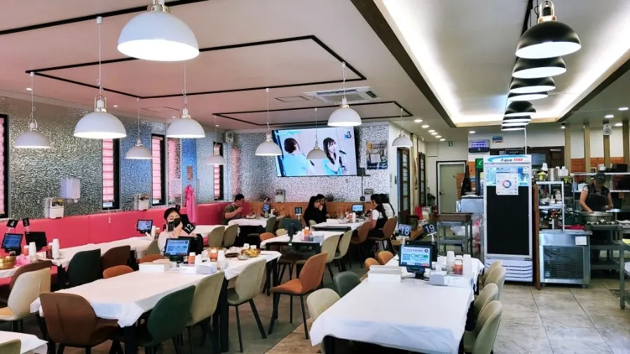 Spacious interior of Ppwang Mulhoe with white plastic sheeting on the tables