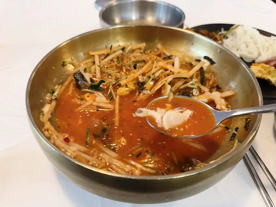 A bowl of mulhoe mixed with sauce and seafood before adding broth