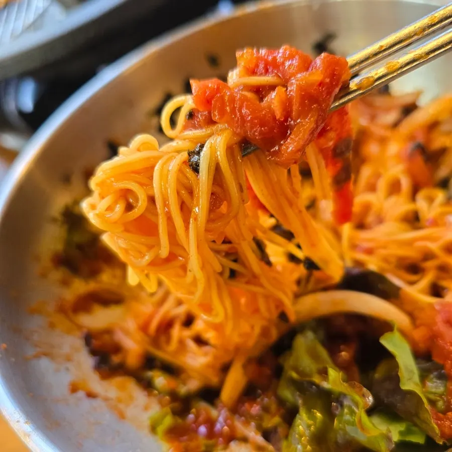 Beef tartare bibim noodles lifted with chopsticks
