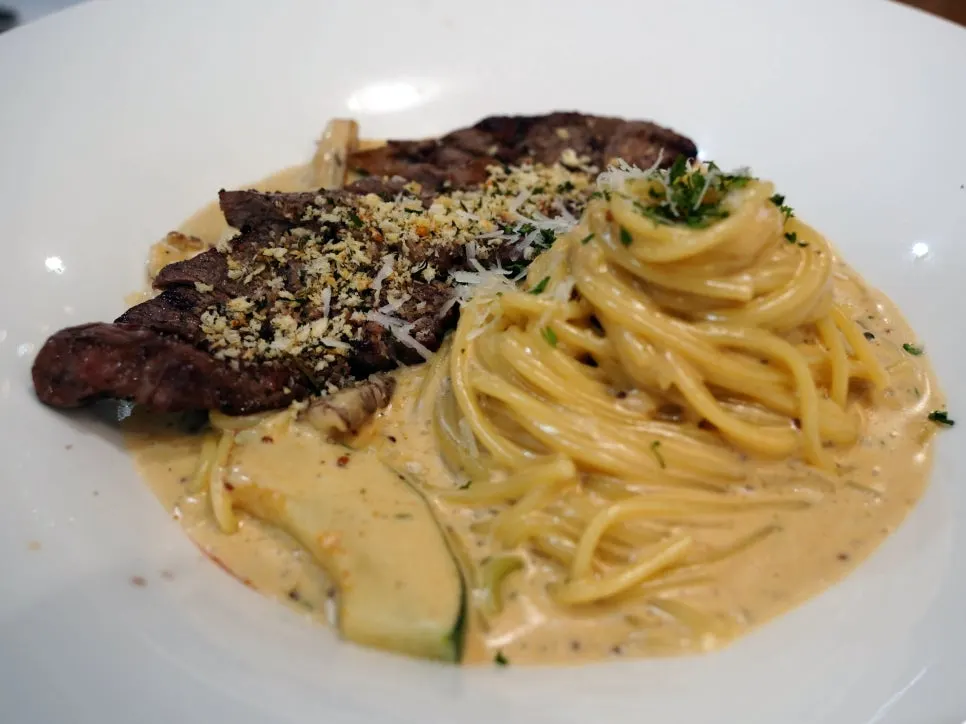 Steak cream pasta topped with salchisal