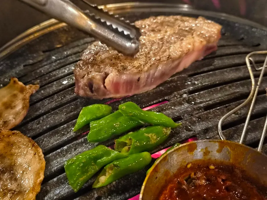 A thick chunk of pork neck placed on the grill