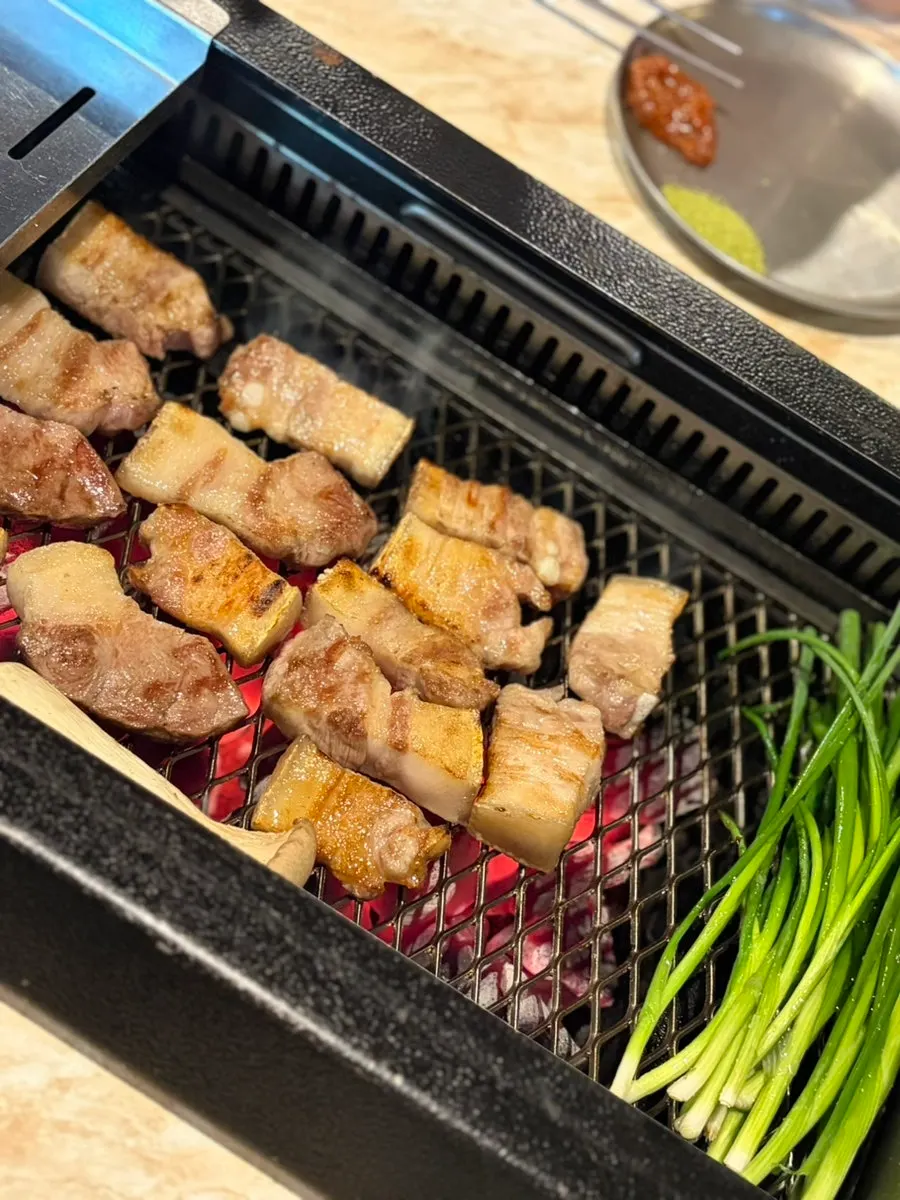 Black pork lined up in a row while grilling
