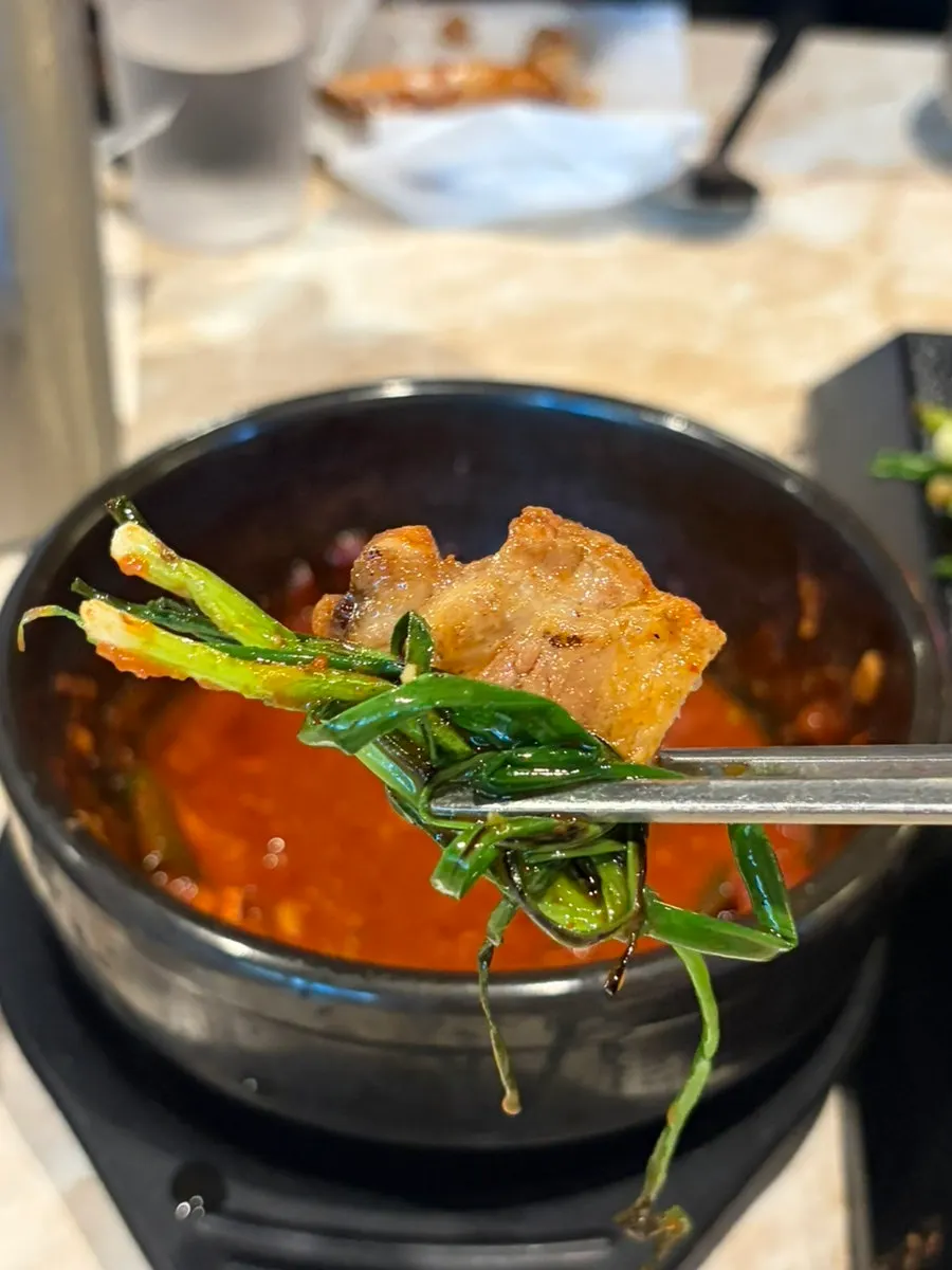 A piece of black pork dipped in meljorim and wrapped in scallion