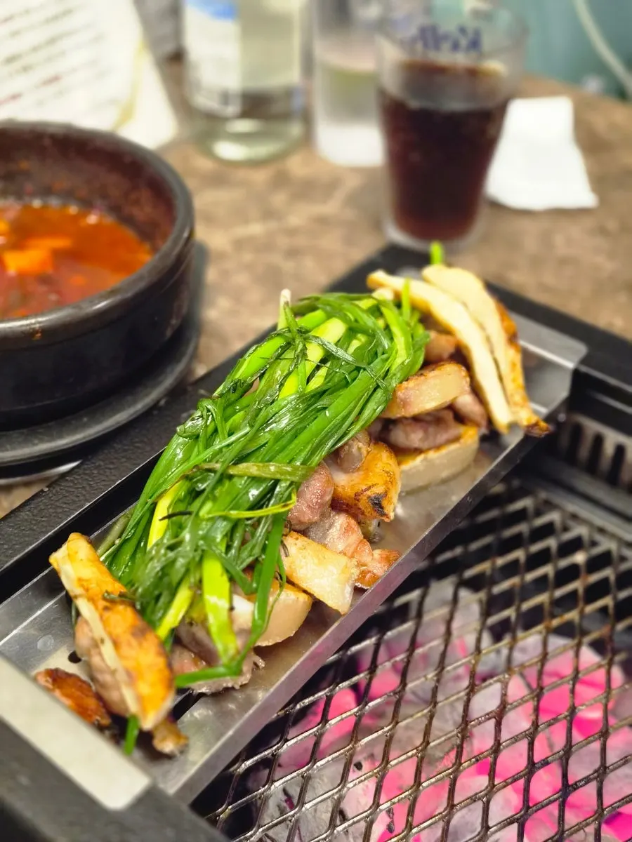 A grilled bite of black pork with shredded scallion and mushroom