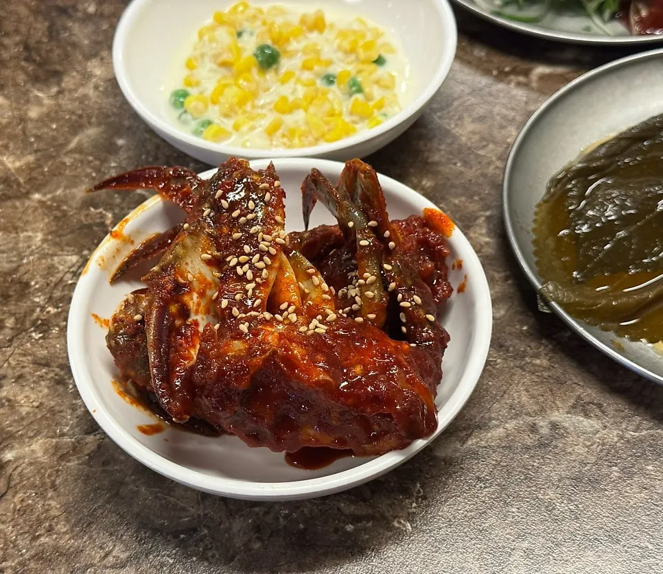 Full table of side dishes including fresh kimchi and seasoned raw crab