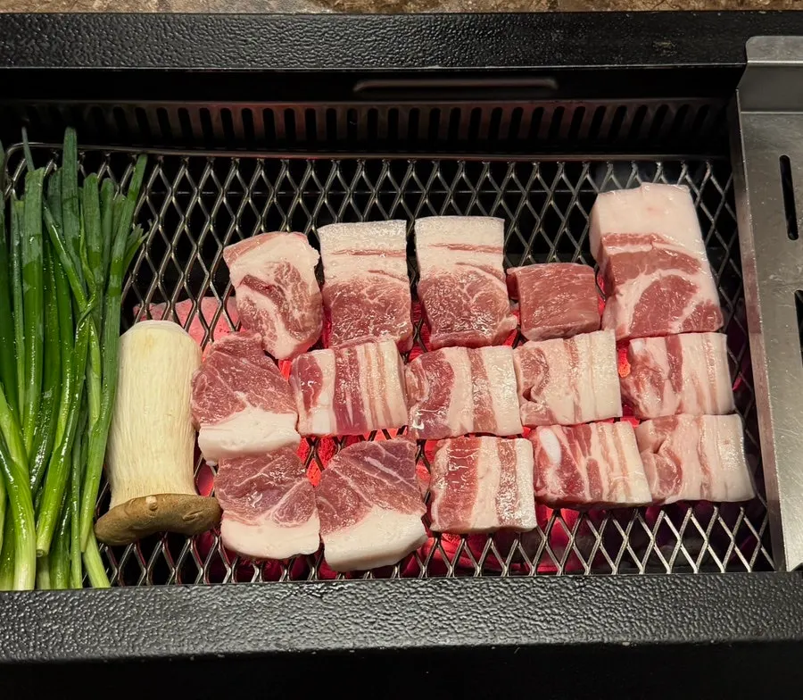 Black pork being grilled tableside as part of the staff service