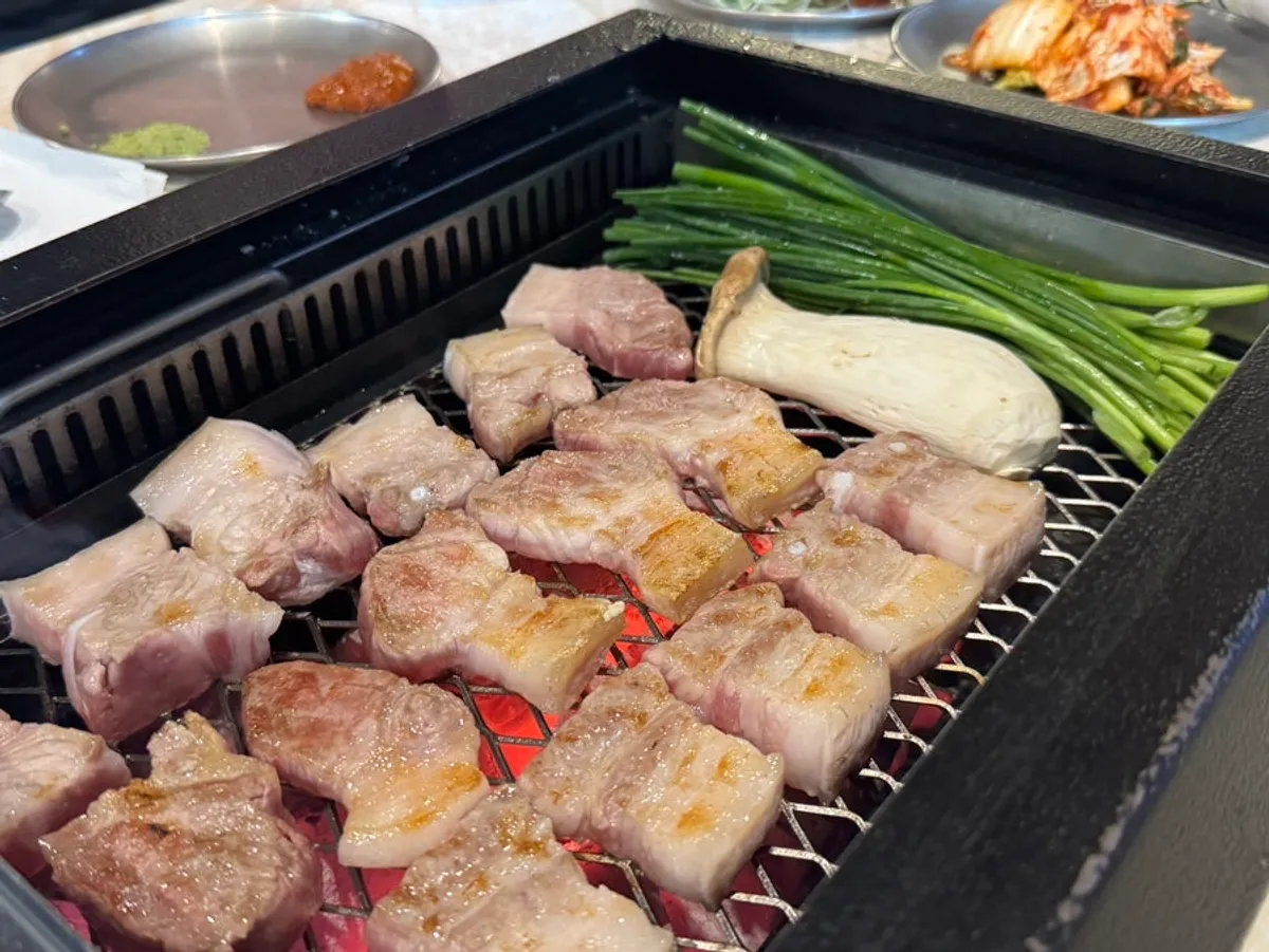Mel-jorim in a stone bowl next to grilling black pork