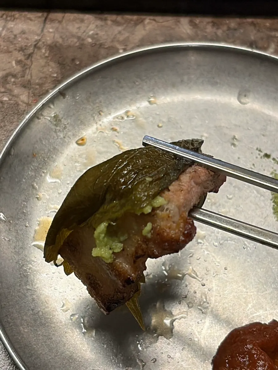 A bite of black pork topped with ssamjang and scallion salad