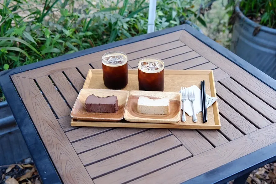 Two cups of coffee and two slices of cake on an outdoor table