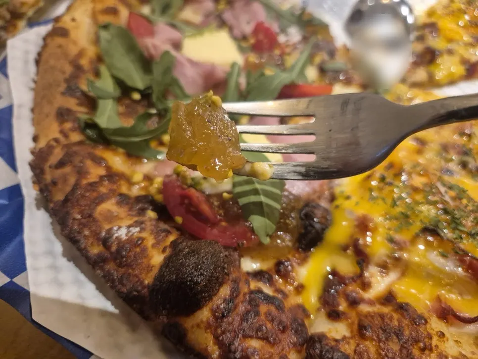 A slice of fig jambon beurre arugula pizza topped with fig jam
