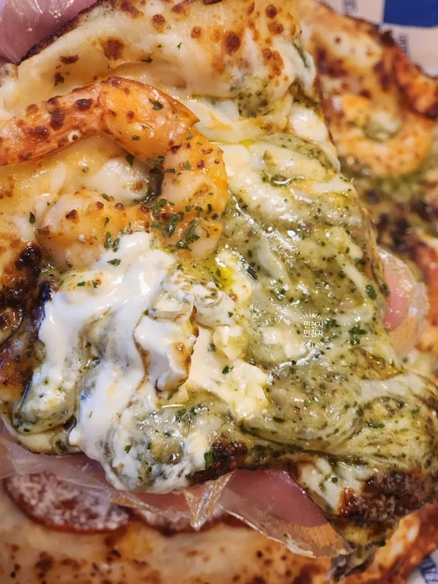 A slice of basil mascarpone shrimp pizza topped with plump shrimp