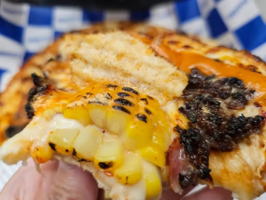 Slice of Amazing Shrimp pizza showing corn salad-style corn kernel topping