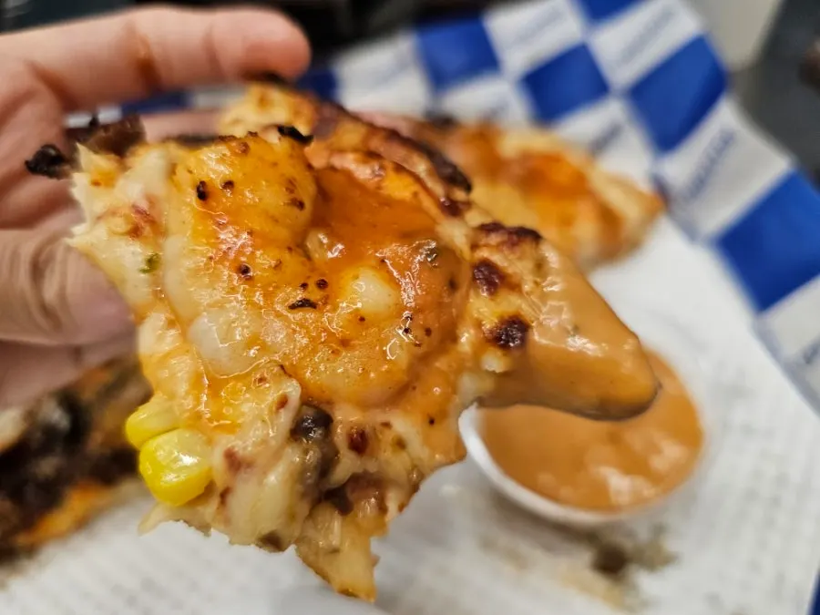Slice of Amazing Shrimp pizza with plump shrimp under a potato chip