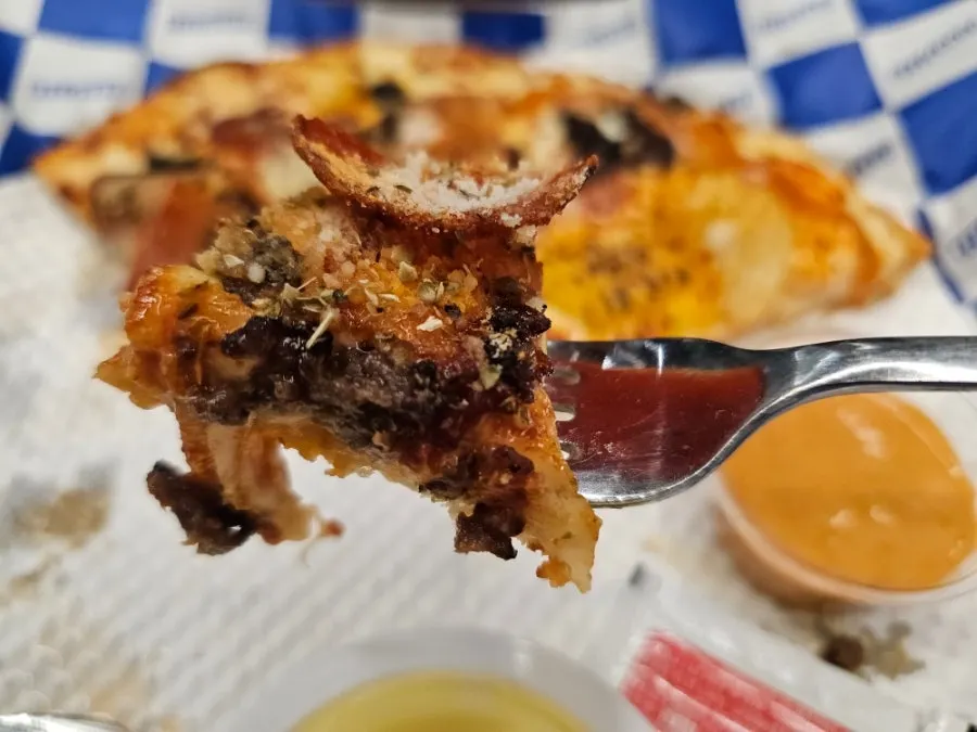 Slice of Mad Max American pizza with bacon, bulgogi, and pepperoni