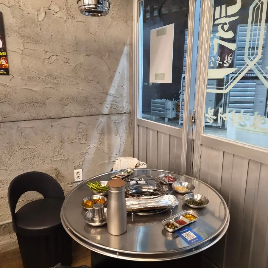 노출 콘크리트 벽과 배기 후드가 보이는 푸짐곱창 매장 내부