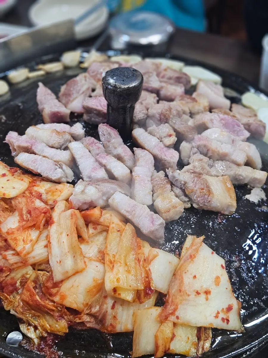 Daging babi dan kimchi dipanggang di atas tutup kuali besi