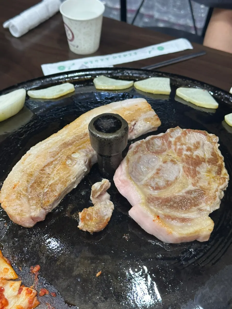 직원이 솥뚜껑에 고기를 구워주는 모습