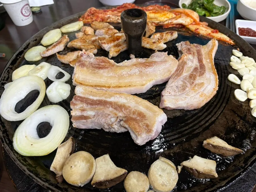 Potatoes, onions, mushrooms, garlic, and kimchi grilling alongside the pork