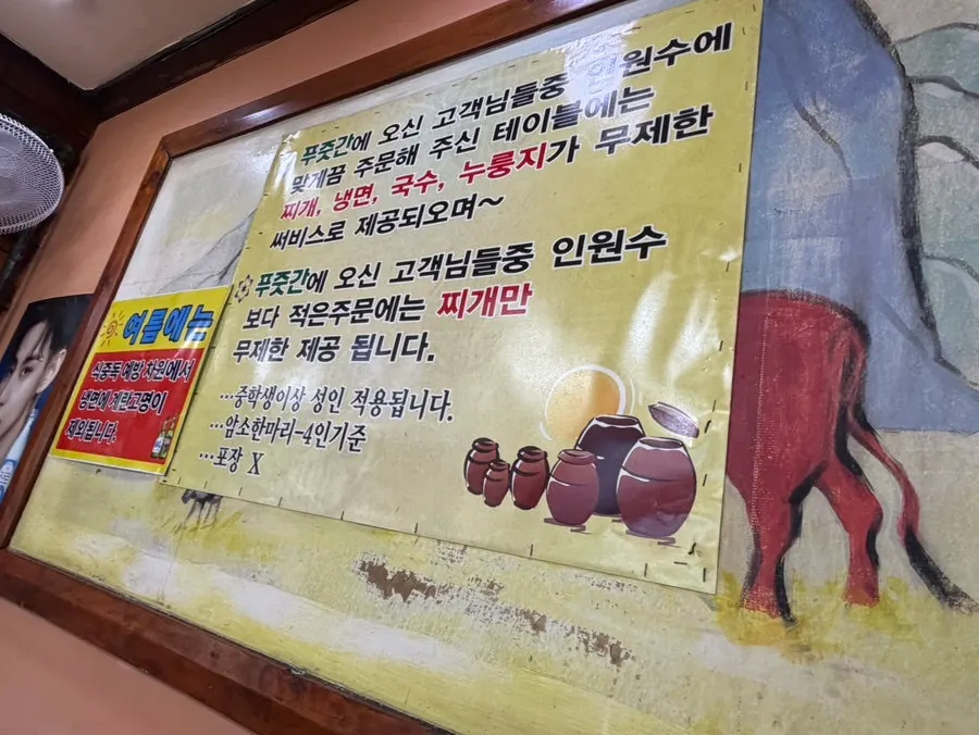 Sign explaining unlimited free stew, naengmyeon, noodles, and scorched rice