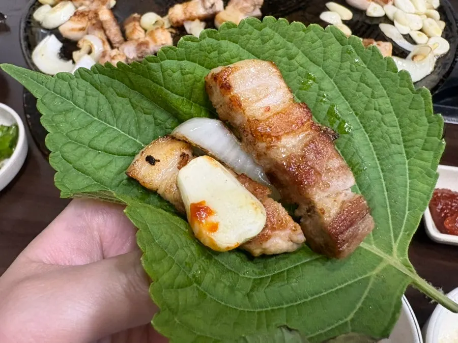 A bite of pork belly with kimchi and vegetables