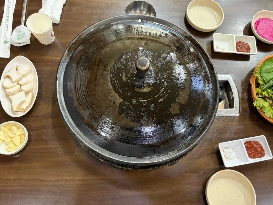 Cauldron-lid grill set up with basic side dishes