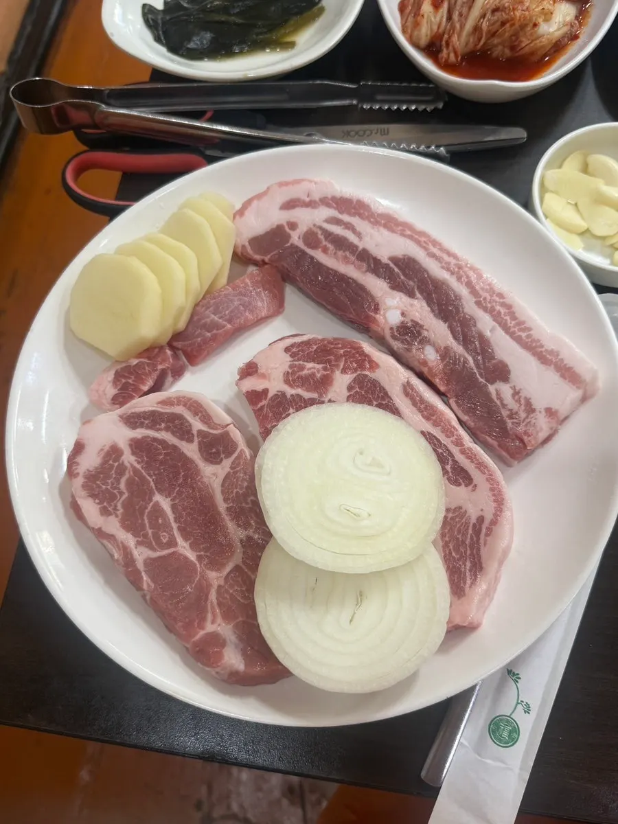 Two servings of pork neck and one of raw pork belly, with onion and potato