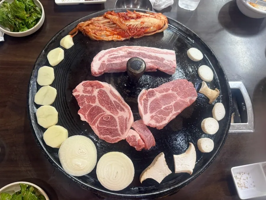 Raw meat placed on the cauldron lid, starting to grill