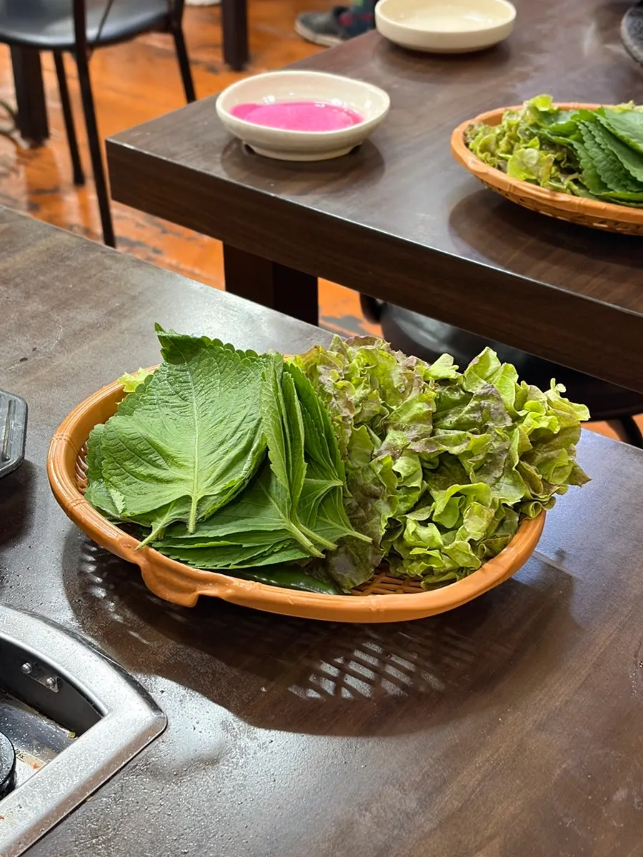 A piece of pork neck wrapped in perilla leaf and lettuce
