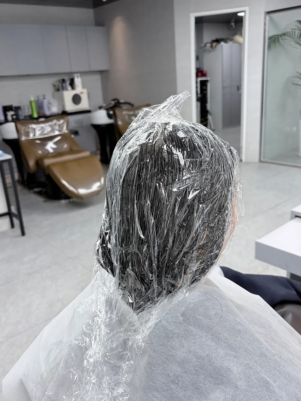 Hair wrapped in film after chemical application for straightening