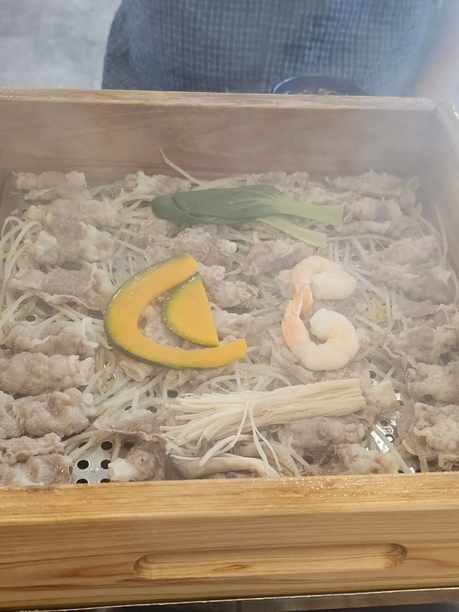 뚜껑을 연 편백찜 속 우삼겹