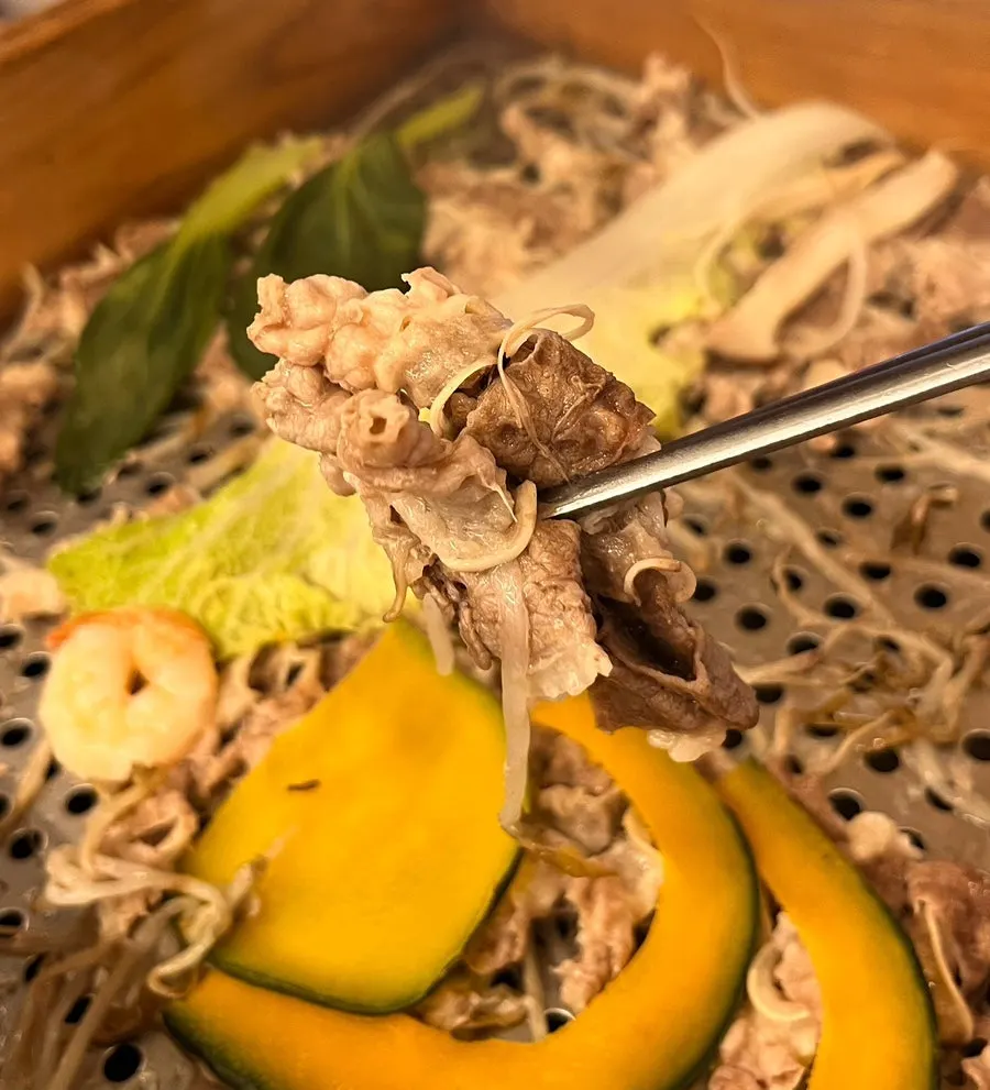 Meat and vegetables inside the opened cedar-steamed pork pot