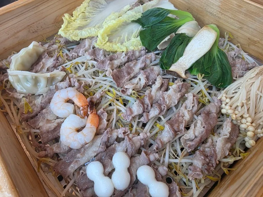 Meat and bean sprouts inside the opened cypress steamer