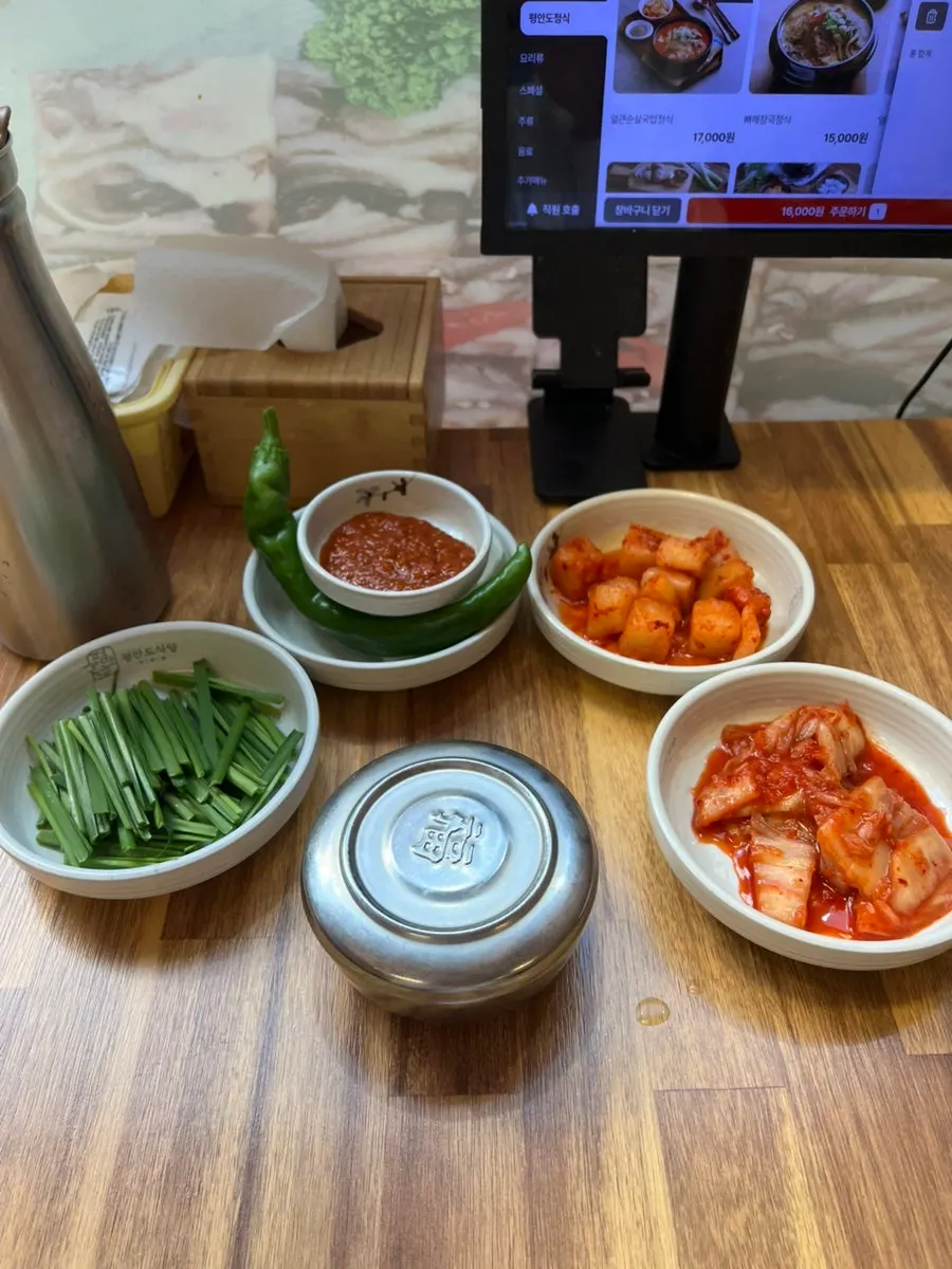 Side dishes of chives, chili peppers, onion, kimchi, and kkakdugi