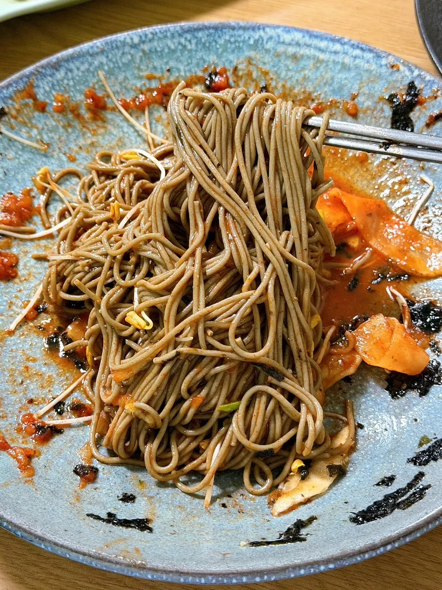 젓가락으로 들어올린 메밀 비빔국수 면발
