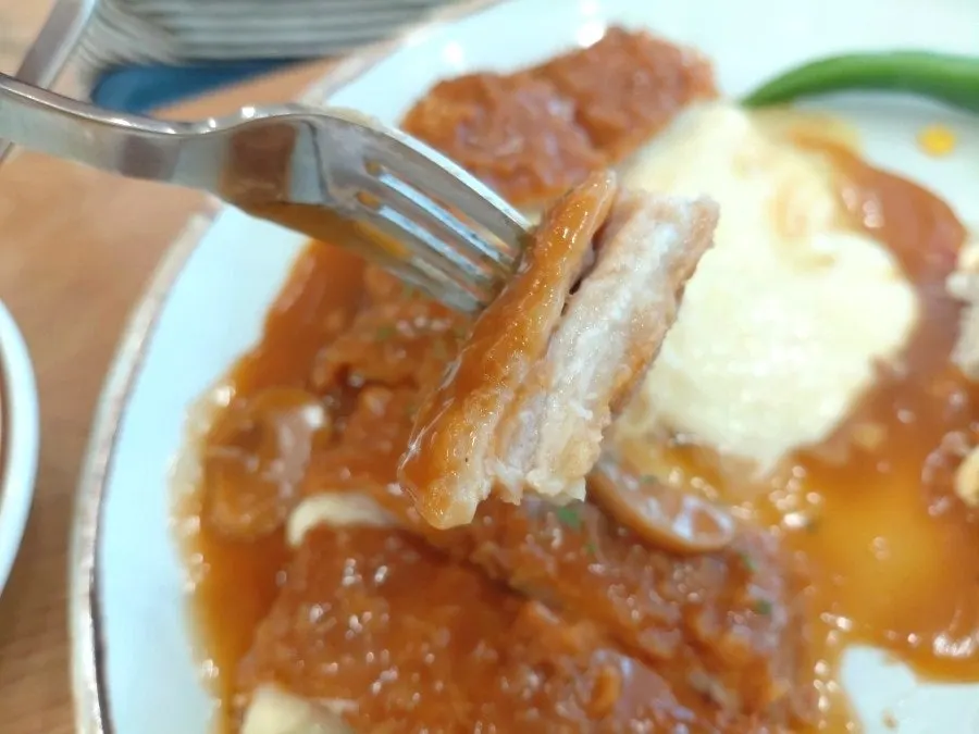 A piece of donkatsu with melted mozzarella cheese flowing out