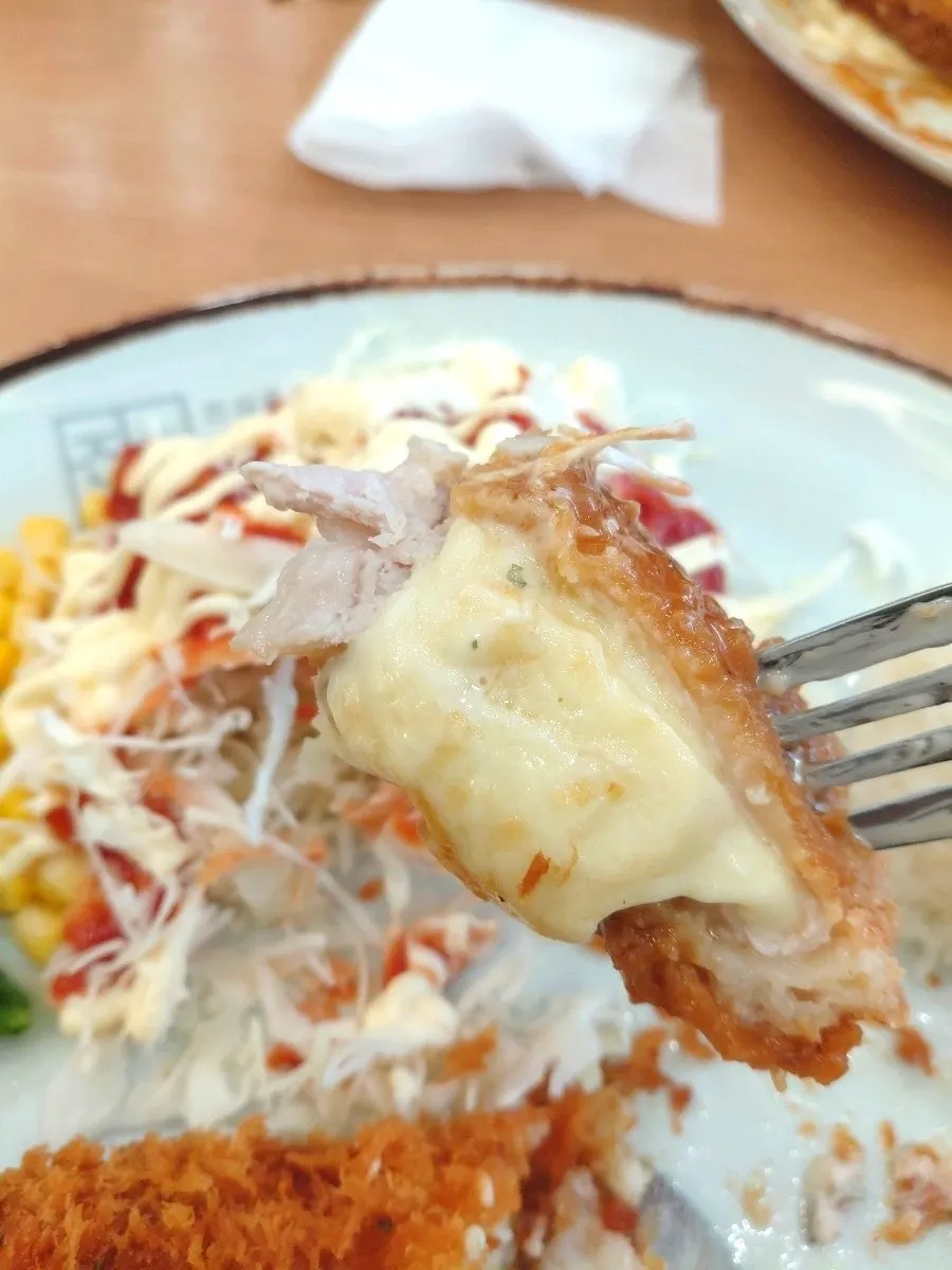 Chopsticks lifting a piece of cheese donkatsu