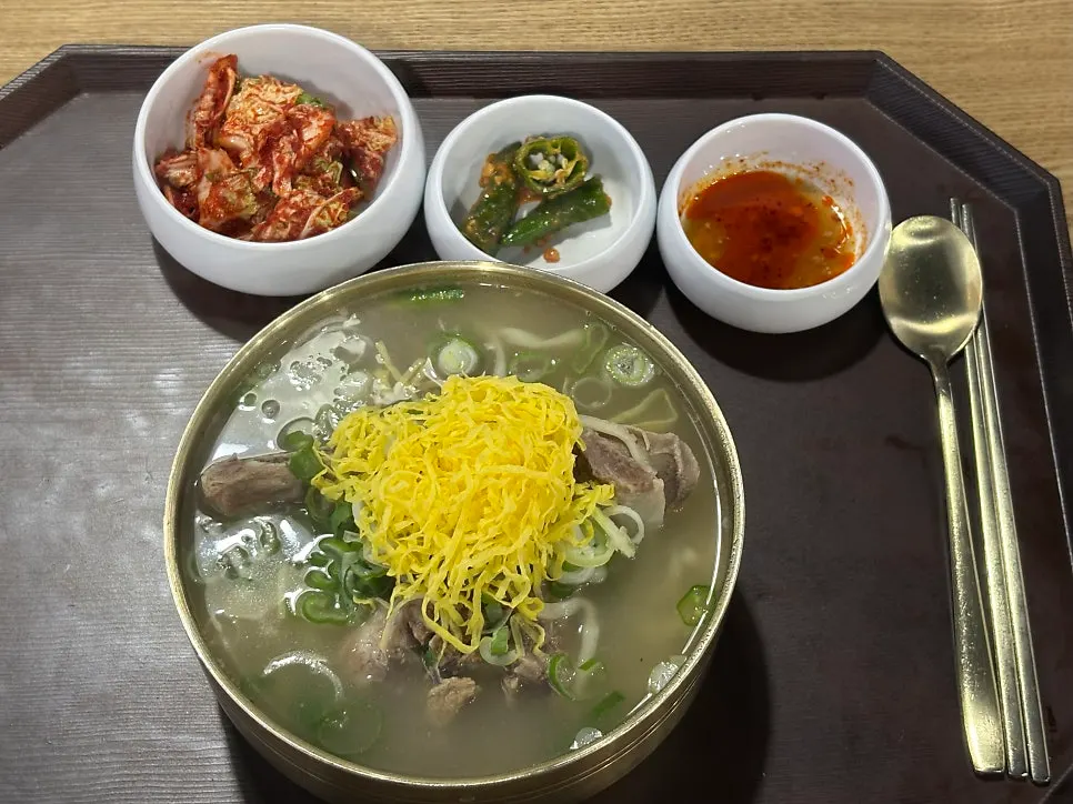 A generously filled bowl of bone kalguksu with broth nearly overflowing
