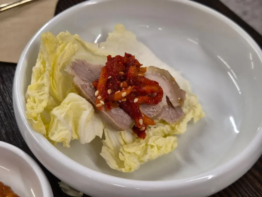 A napa cabbage wrap topped with pork, salted shrimp, and radish salad