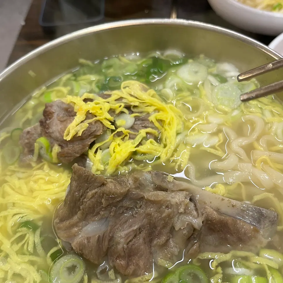 Pork bone kalguksu topped generously with egg garnish and green onion