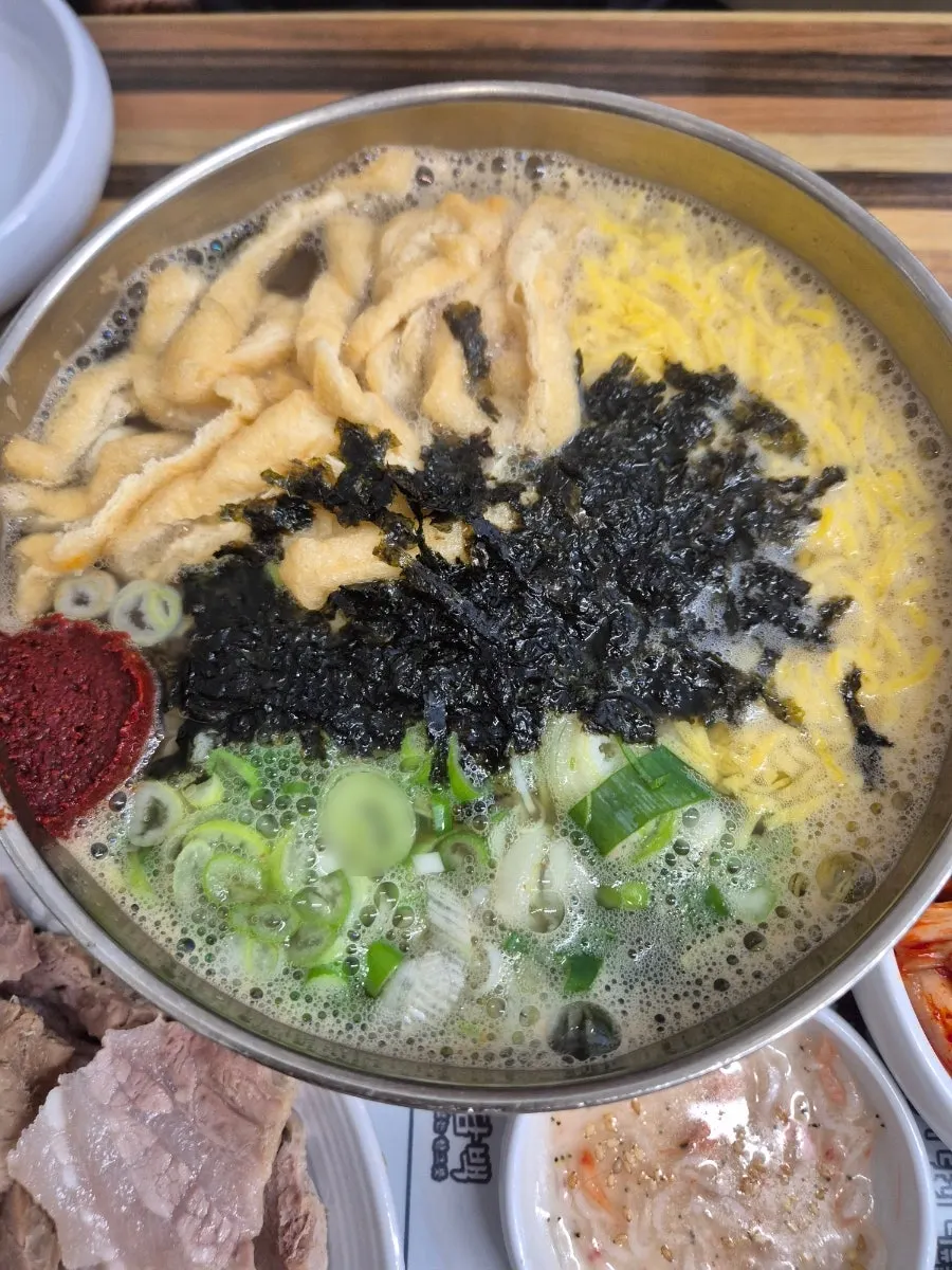 A bowl of Namhae anchovy kalguksu topped with garnishes